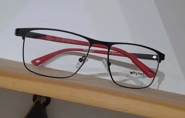 Armazón metálico negro con varillas rojas apoyado sobre un estante de madera.
